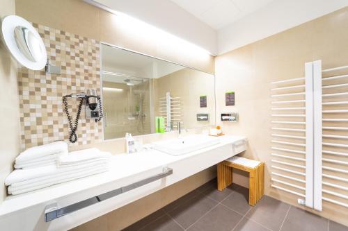 ein Bad mit einem Waschbecken und einem Spiegel in der Unterkunft Hotel Jozef in Idrija