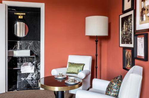a living room with orange walls and white chairs and a table at 4F Boutique Hotel Florence in Florence