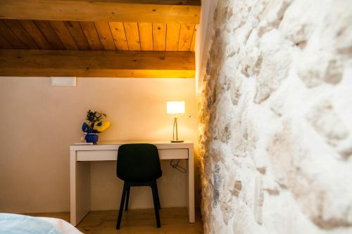a bedroom with a desk and a chair next to a stone wall at Dimora Bennardo in Palazzolo Acreide