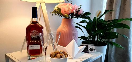 a bottle of wine on a table with flowers and a vase at Apartment Holata 201 in Hradec Králové