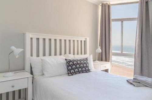 a bedroom with a bed with a view of the ocean at 806 Beachfront in Amanzimtoti