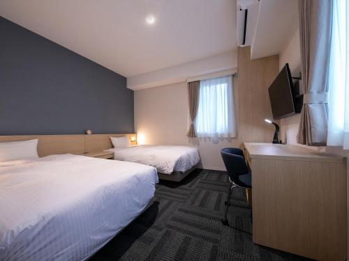 a hotel room with two beds and a desk at Hotel Best Price Kochi in Kochi