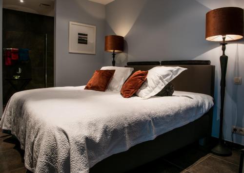 1 dormitorio con 1 cama con sábanas y almohadas blancas en Scheldeoever, en Temse