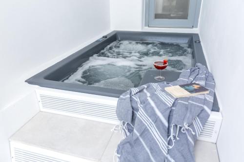 a bath tub with a glass of wine in it at Margarita Hotel in Firostefani