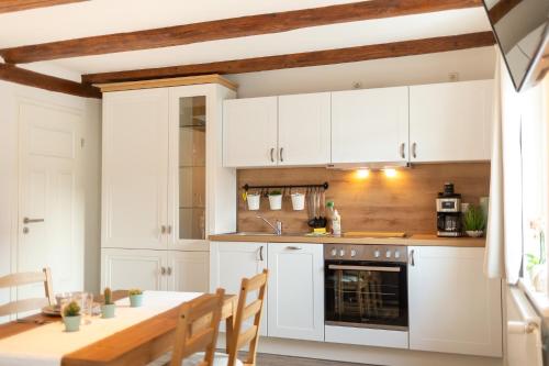 a kitchen with white cabinets and a wooden table at Ferienwohnung zum Marktplatz in Wernigerode