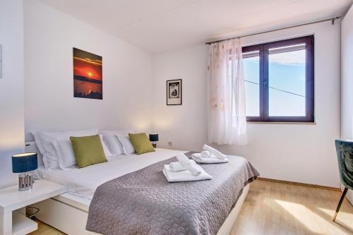 ein weißes Schlafzimmer mit einem Bett und einem Fenster in der Unterkunft APARTMENT MATEO in Miholašćica