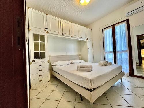 a bedroom with a bed with white cabinets and a window at Appartamento A un passo dal mare in Porto Pozzo