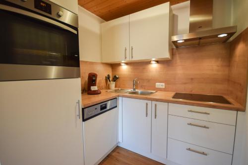 a kitchen with white cabinets and a sink at Haus Schönblick in Kirchberg in Tirol