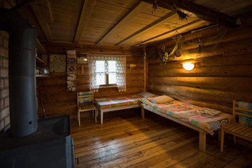 - une chambre avec 2 lits et une fenêtre dans une cabane en rondins dans l'établissement Auru Cīruļi, à Auri