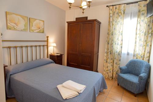 um quarto com uma cama azul e uma cadeira azul em Hostal Rural Zahara em Zahara de la Sierra