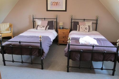 a bedroom with two beds and a chair at Burnt Mill Cottage in Burnham on Crouch