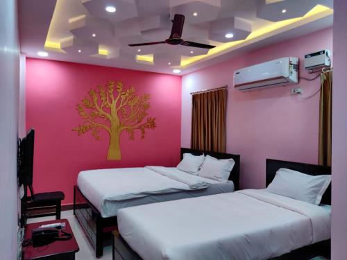 two beds in a room with a pink wall at Temple stay - Uma Residency and Guest House in Mayiladuthurai