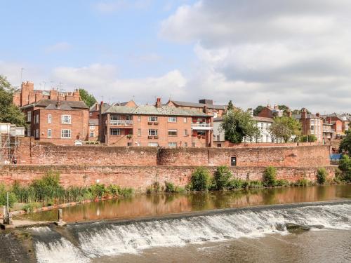 a waterfall in front of a river with buildings in the background at Dee Heights Penthouse in Chester