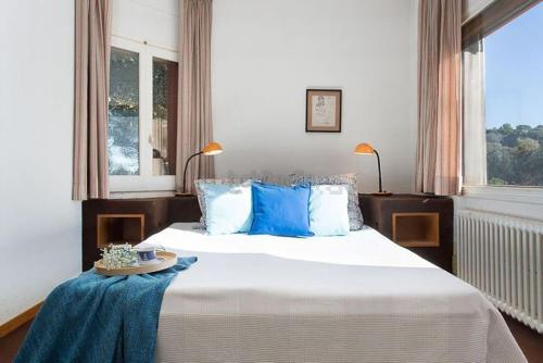 a bedroom with a large white bed with blue pillows at El Chalet del Montseny in Seva