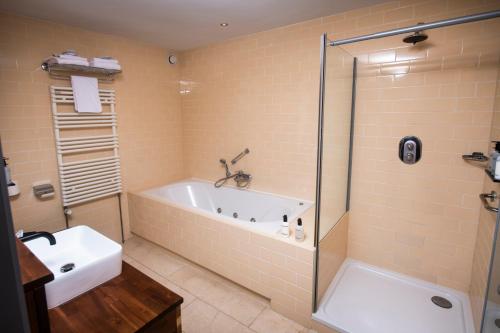a bathroom with a tub and a sink and a shower at Nobel Hotel Ameland in Ballum