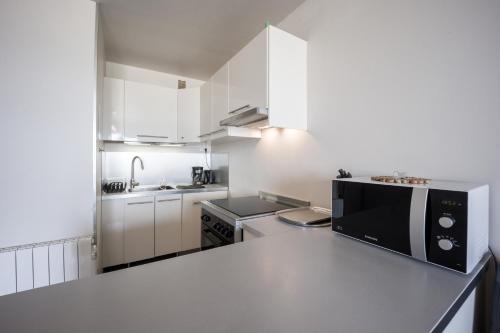 une petite cuisine avec des armoires blanches et un micro-ondes dans l'établissement Trimaran, à Courseulles-sur-Mer