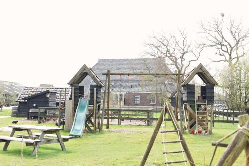 a playground with wooden play equipment in a park at Smuk Lytse Bell Tent in Echtenerbrug