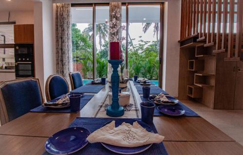 a dining room table with blue dishes and a red candle at The Cloverleaf Super Luxury Villa Goa With Private Pool, North Goa in Candolim