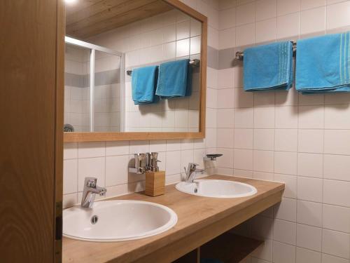 a bathroom with two sinks and a mirror and blue towels at Appartements Duengler in Schruns-Tschagguns