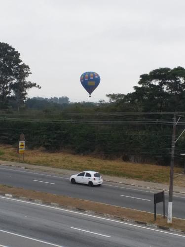 a car driving down a road with a hot air balloon at POUSADA PERLLA's Pindamonhangaba in Pindamonhangaba