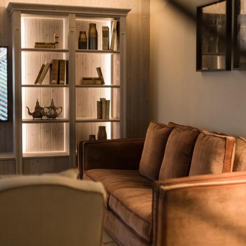 a living room with a brown couch and shelves at La Collina dei Ciliegi in Grezzana