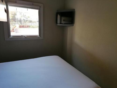 Bett in einem Zimmer mit Fenster in der Unterkunft SUN1 WITBANK in Witbank