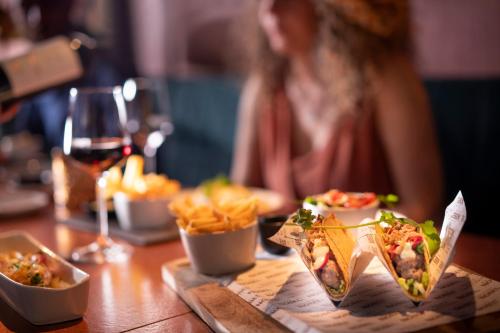 a woman sitting at a table with food and a glass of wine at Nobel Hotel Ameland in Ballum