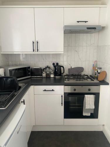 a kitchen with white cabinets and a stove top oven at Central Brighton garden studio, close to seafront in Brighton & Hove