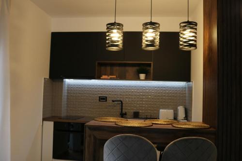 a kitchen with a counter with chairs and lights at W Apartman in Vrnjačka Banja