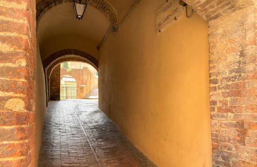 an alley way with a brick wall and an archway at CAMPOREGIO 31- In Centro con Vista sul Duomo in Siena