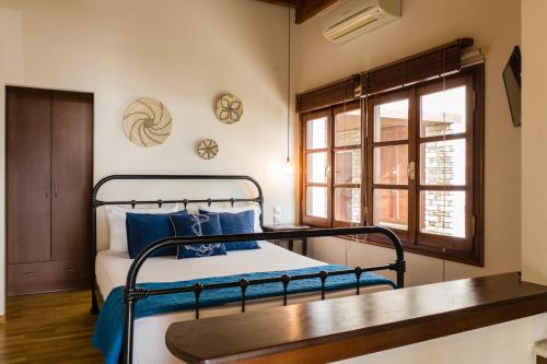 Un dormitorio con una cama con almohadas azules y una ventana en Zouzoulas Filoxenia - Koralia Apartments, en Milina