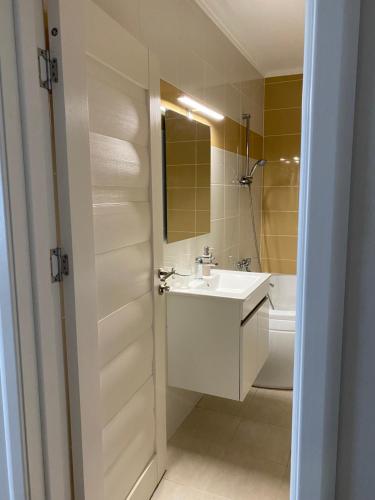 een witte badkamer met een wastafel en een bad bij Apartament AVANA in Oradea