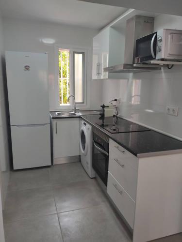 a white kitchen with a sink and a dishwasher at El Rinconcito Cubano en la playa in Almería