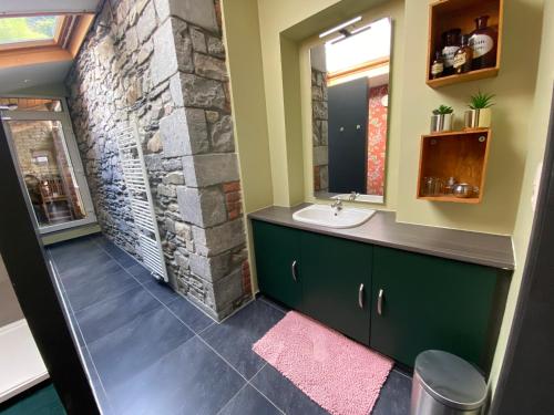 a bathroom with a stone wall and a sink at Berthe Artist House in La-Roche-en-Ardenne