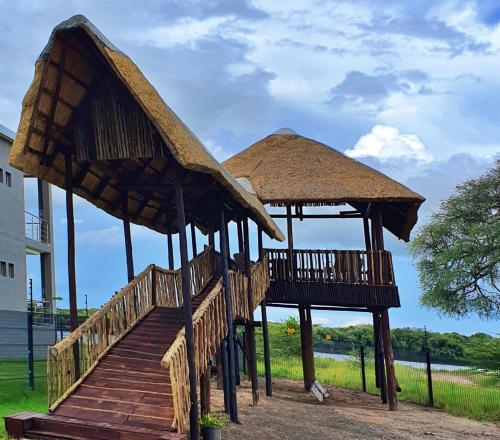 a pair of huts with a wooden staircase at Tlou Safari Lodge in Kasane