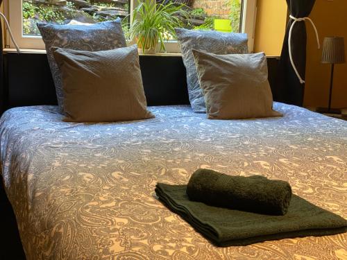 a bed with pillows and a green towel on it at Berthe Artist House in La-Roche-en-Ardenne