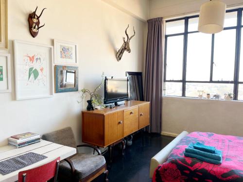 um quarto com uma cama e uma secretária com uma televisão em Modern city apartment in Johannesburg - Maboneng em Joanesburgo
