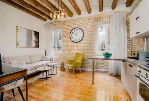 a living room with a couch and a clock on a brick wall at Curcumelli Luxury Suites - ΚΟΡΚΥΡΑ in Corfu