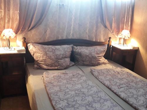 Un dormitorio con una cama con dos mesitas de noche y dos lámparas. en Borgáta Retro Apartman, en Borgáta