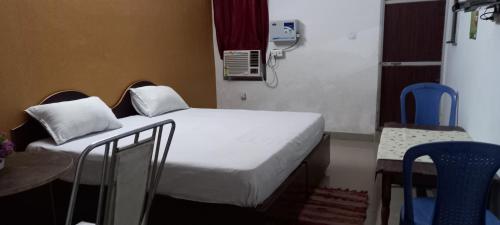 a small room with a bed and a table and chairs at vindhyvasini guest house in Kushinagar