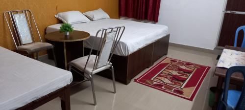 a small room with a bed and a table and chairs at vindhyvasini guest house in Kushinagar