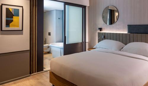a bedroom with a large white bed and a bathroom at Hyatt Regency Cape Town in Cape Town