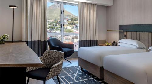 a hotel room with two beds and a table and chairs at Hyatt Regency Cape Town in Cape Town
