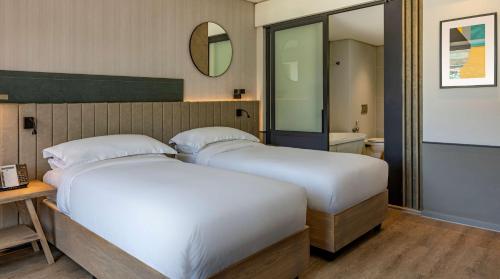 two beds in a hotel room with a mirror at Hyatt Regency Cape Town in Cape Town