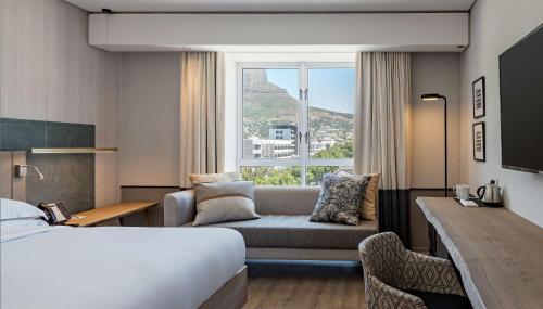 a hotel room with a bed and a couch and a window at Hyatt Regency Cape Town in Cape Town