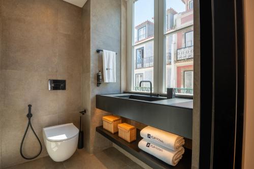 a bathroom with a sink and a toilet and a window at Ferraria XVI FLH Hotels Lisboa in Lisbon