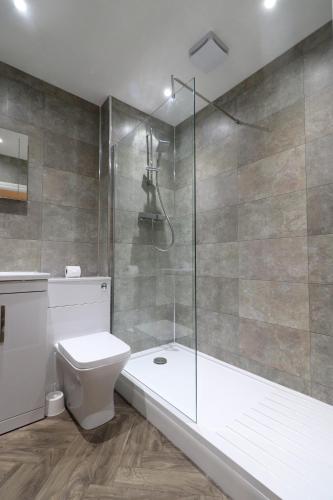 St George's Lodge, Bisley في Brookwood: حمام مع دش ومرحاض وحوض استحمام