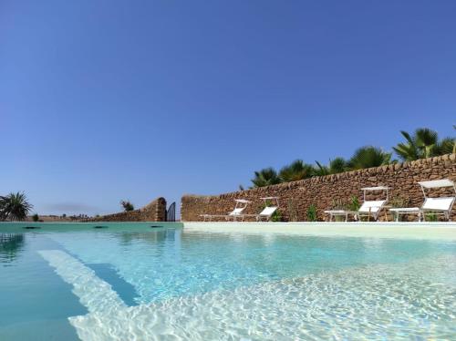 a swimming pool with chairs and a resort at Feudo Nobile in Gela