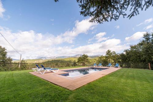 a backyard with a swimming pool and two lawn chairs at Casa Rural Moixella in Lladurs