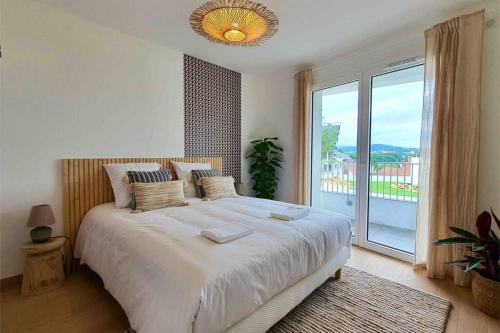 une chambre avec un grand lit et une grande fenêtre dans l'établissement Le Bohème Beau T2 vue lac & montagnes + garage, à Annecy
